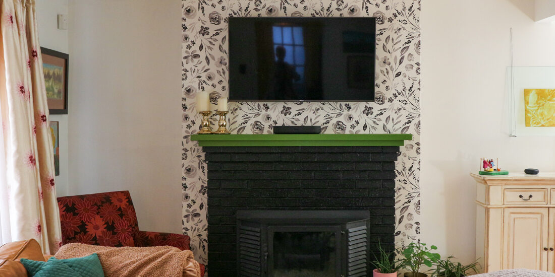black fireplace green mantel with black and white floral wallpaper