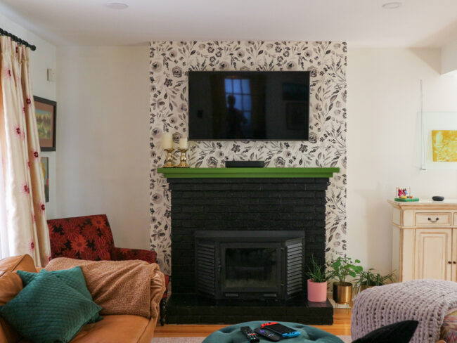 black fireplace green mantel with black and white floral wallpaper